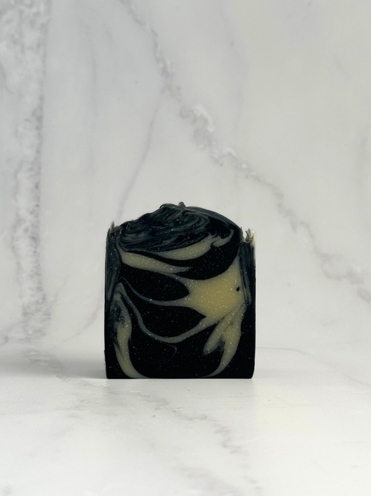 Detox Bar by Dew Kind – hand-crafted in Aotearoa with BioGro-certified organic tallow, activated charcoal, and kaolin clay, black and white marbled bar on marble background